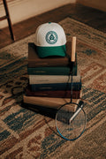 La Casquette Club Lévites posée sur une pile de bibles, ambiance club — Lévites Paris
